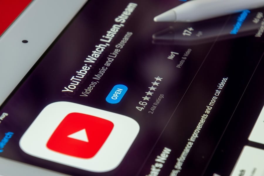 Close-up of an iPad showing the YouTube app page in the App Store with the Open button, a 4.6-star rating, and an Apple Pencil near the screen.